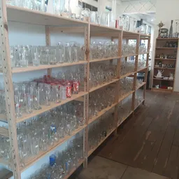 Houten stellingen met grote verzameling glazen flessen en bokalen, georganiseerd op meerdere niveaus