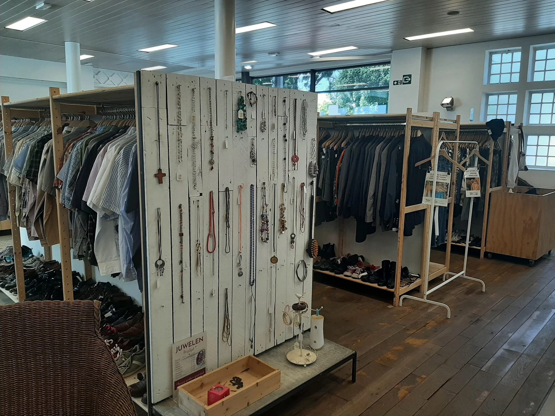 Rekken en displaystanders met tweedehands kleding en accessoires in de winkel