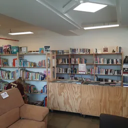 Boekenrekken en kasten vol met boeken en media in een bibliotheekachtige ruimte met zitbank