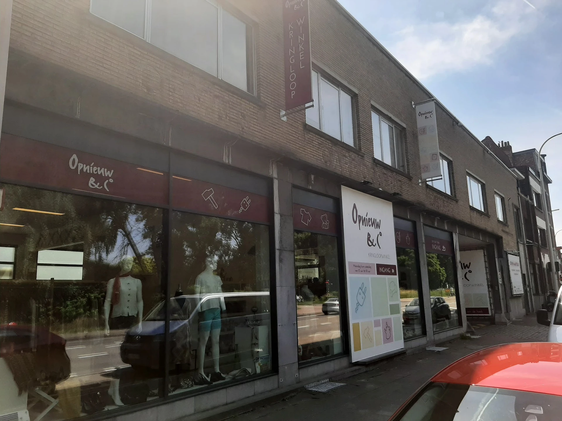 Gevel van kringloopwinkel met etalageruiten, winkelnaam en uitstallingen zichtbaar