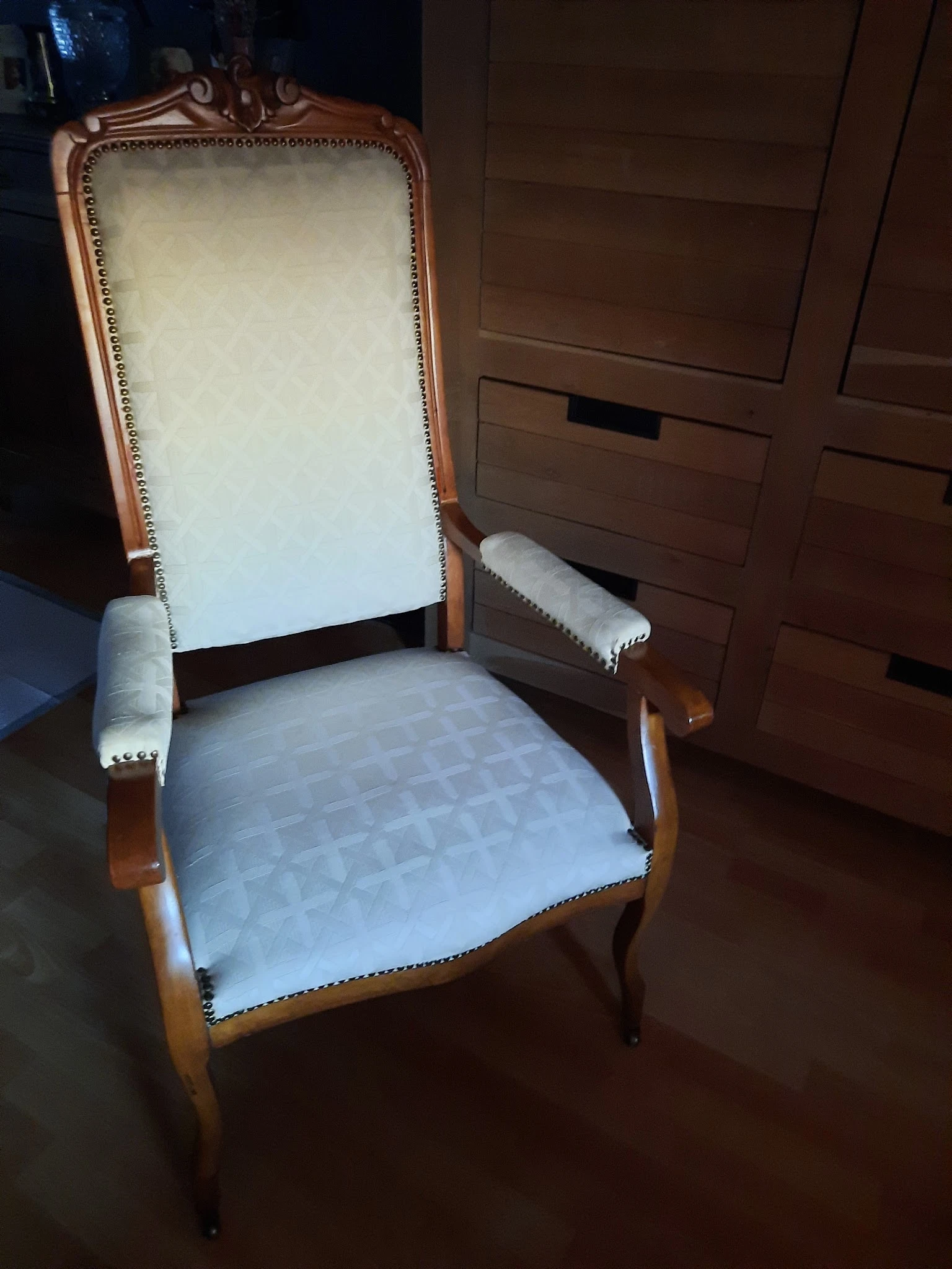 Houten fauteuil met crème-wit bekleding en decoratieve nagels langs de randen