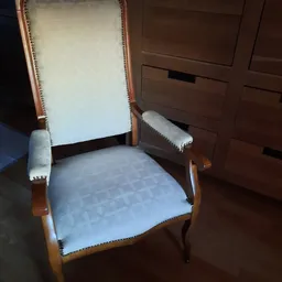 Houten fauteuil met crème-wit bekleding en decoratieve nagels langs de randen
