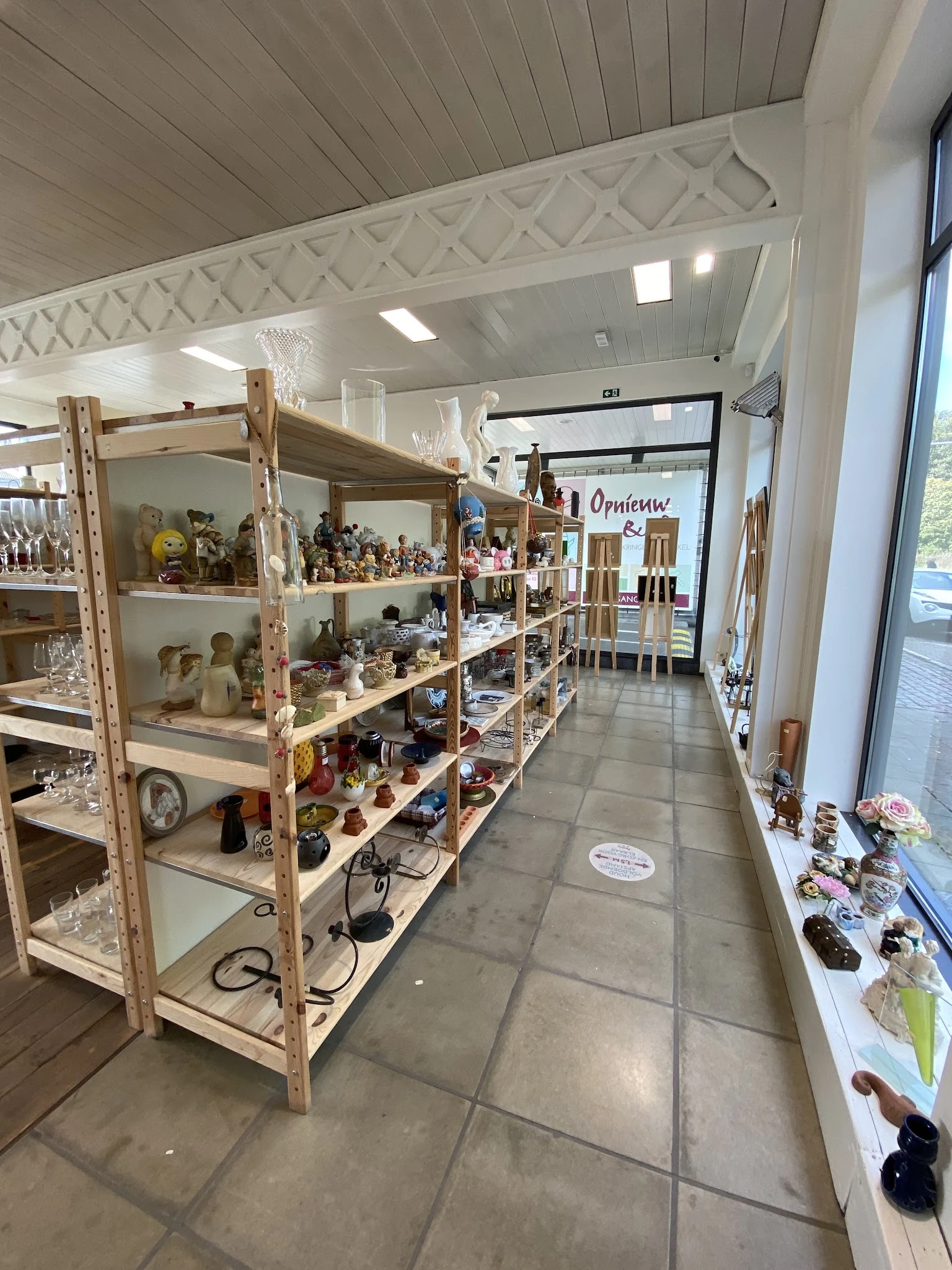 Houten stellingen met verzameling beeldjes, poppen en decoratieve items in winkelruimte