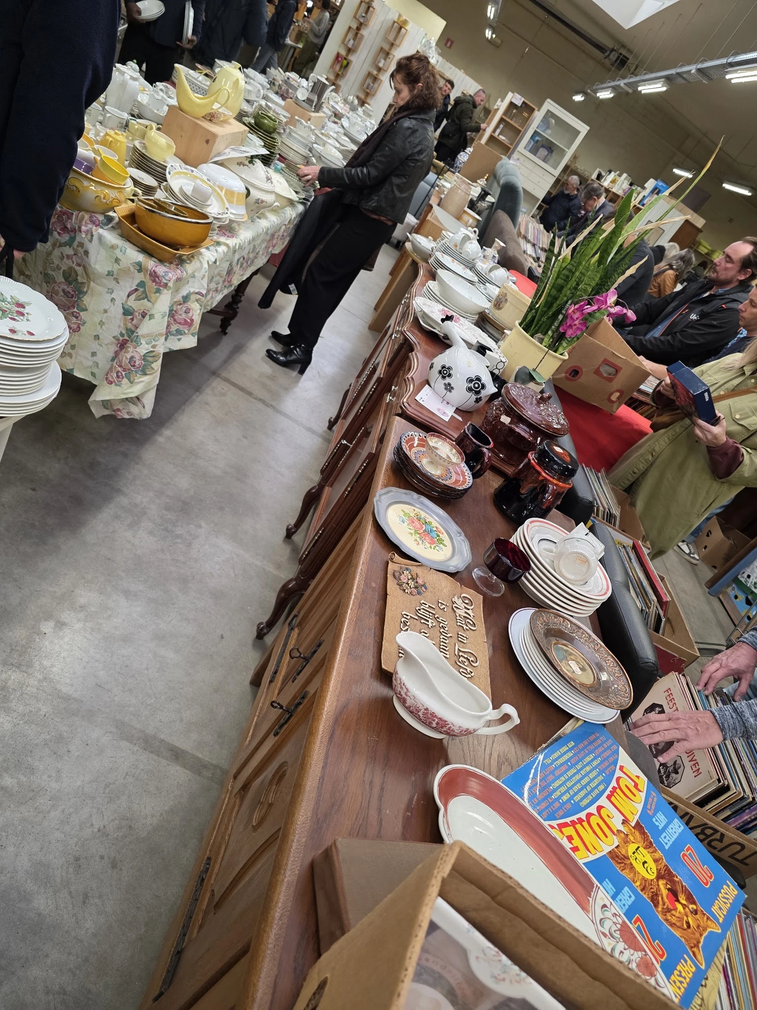 Houten tafel met uitgestalde serviesgoed, borden en aardewerk in verschillende patronen en kleuren