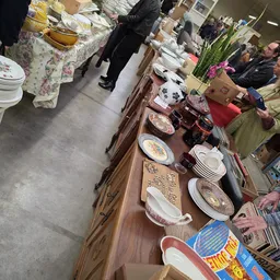 Houten tafel met uitgestalde serviesgoed, borden en aardewerk in verschillende patronen en kleuren