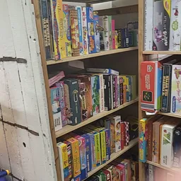 Houten stellingkast met bordspellen, dvd's en boeken netjes uitgestald op drie niveaus