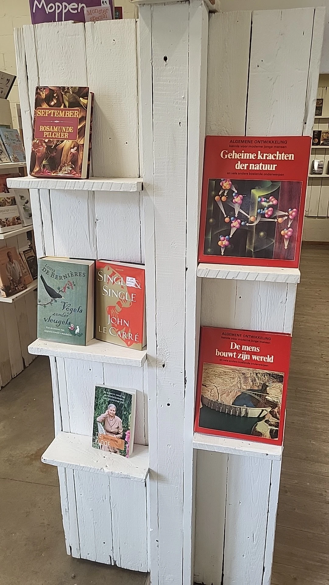 Boekenrek met tweedehands boeken en affiches in een kringloopwinkel