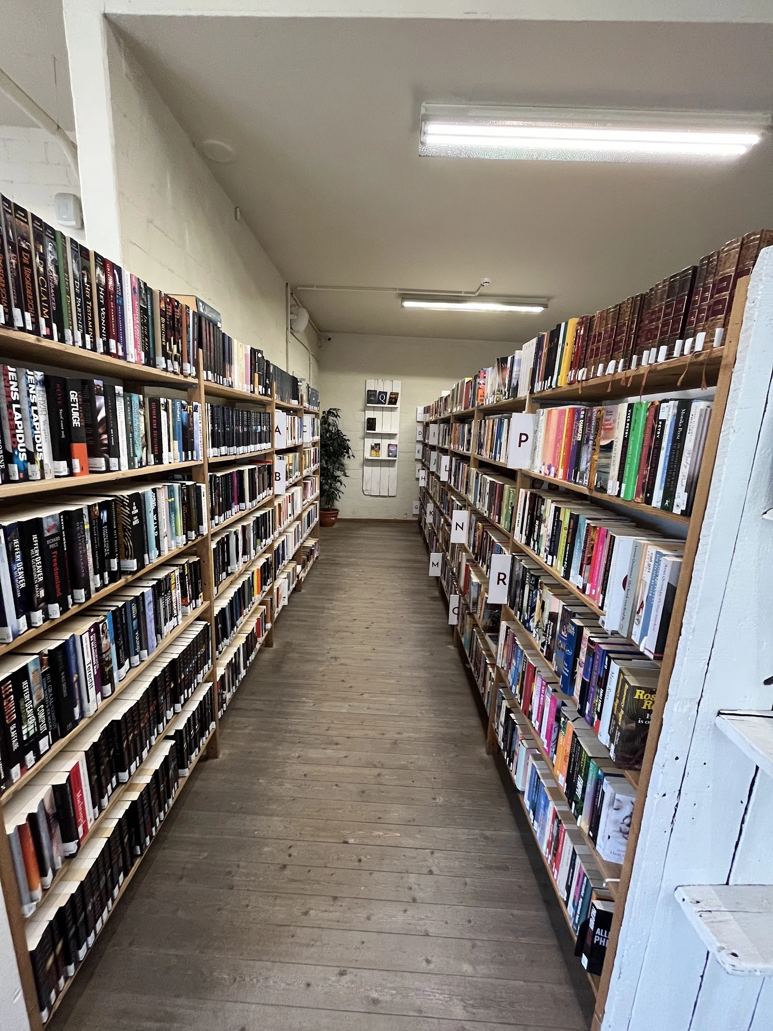 Gang tussen twee stellingen vol met dvd's en blu-rays in een kringloopwinkel