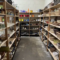 Winkelinterieur met houten stellingen vol huishoudartikelen, manden en serviesgoed
