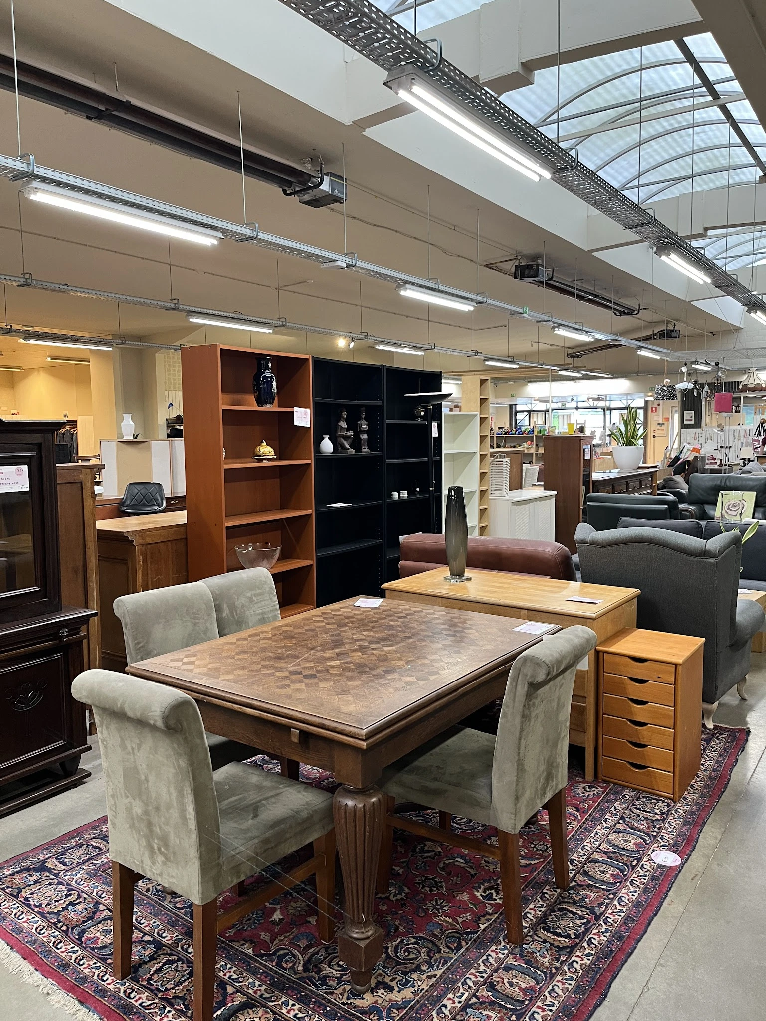 Winkelvloer met houten eettafel, stoelen en kasten met huisraad in een kringloopwinkel