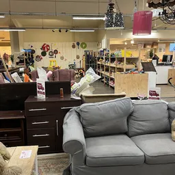 Winkelvloer met meubels zoals banken, kasten en tafels, stellingen met huishoudartikelen en decoraties aan de muur