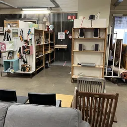 Overzicht van de winkelruimte met houten stellingen, uitgestalde meubels en decoratieartikelen