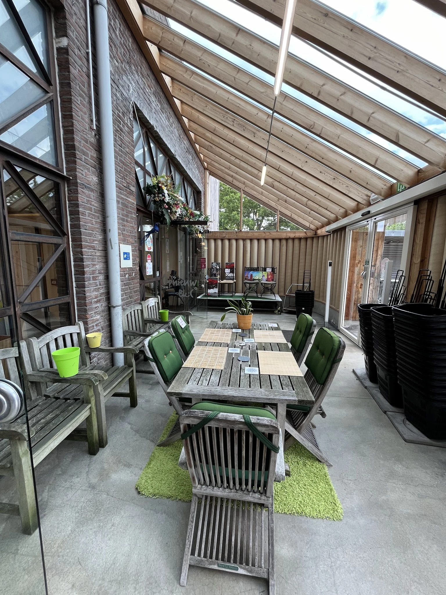 Overdekt terras met tafels en stoelen, uitzicht op winkelruimte met stellingen en winkelartikelen