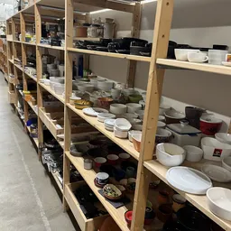 Houten stellingen vol met wit serviesgoed, glazen potten en zwarte keukenartikelen