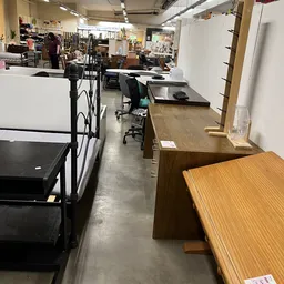 Winkelruimte met houten en zwarte tafels, stoelen en stellingen langs de muur