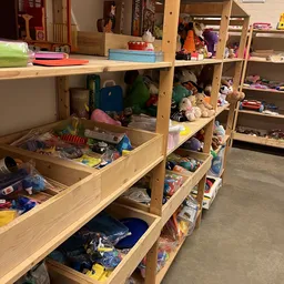 Houten stellingen met speelgoed, knuffels, boeken en diverse tweedehands artikelen in de winkel