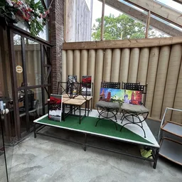 Terras of uitstalkamer met groene vloer, stoelen, tafels en displays tegen muren met beige gordijnen
