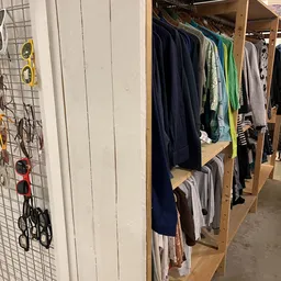 Houten rekken met tweedehands kleding in verschillende kleuren, waaronder donkerblauwe en groene kledingstukken