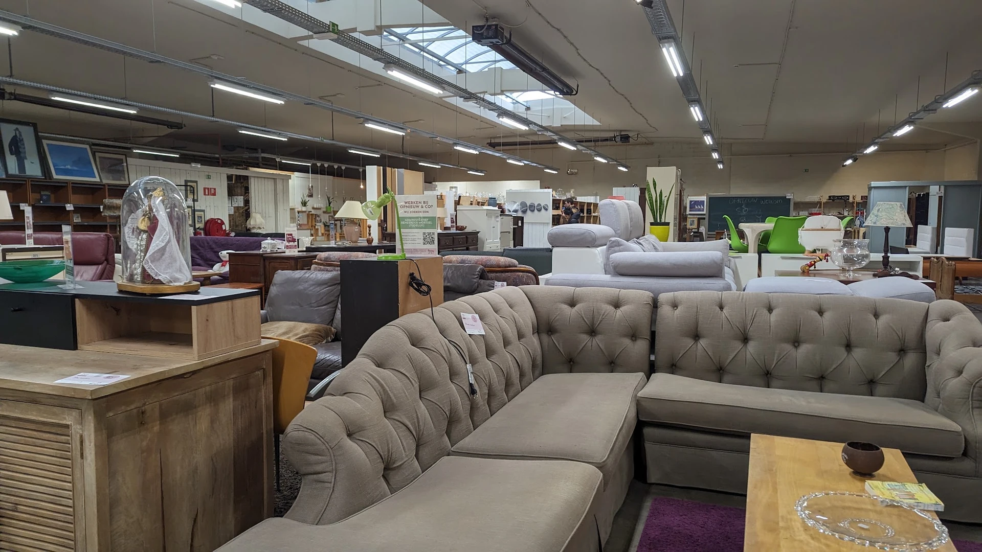 Grijze gestoffeerde banken en fauteuils in de winkel, met meer meubels op de achtergrond