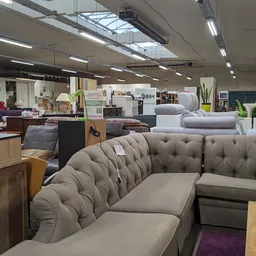 Grijze gestoffeerde banken en fauteuils in de winkel, met meer meubels op de achtergrond