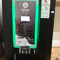 Close-up van een groene koffieautomaat voor Oxfam Fair Trade koffie met touchscreen en instructies