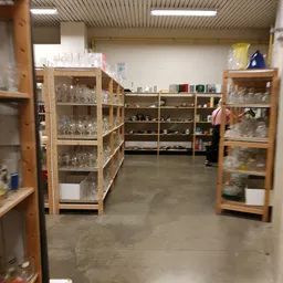 Winkelinterieur met houten stellingen vol met glazen en servies, grijs betonnen vloer