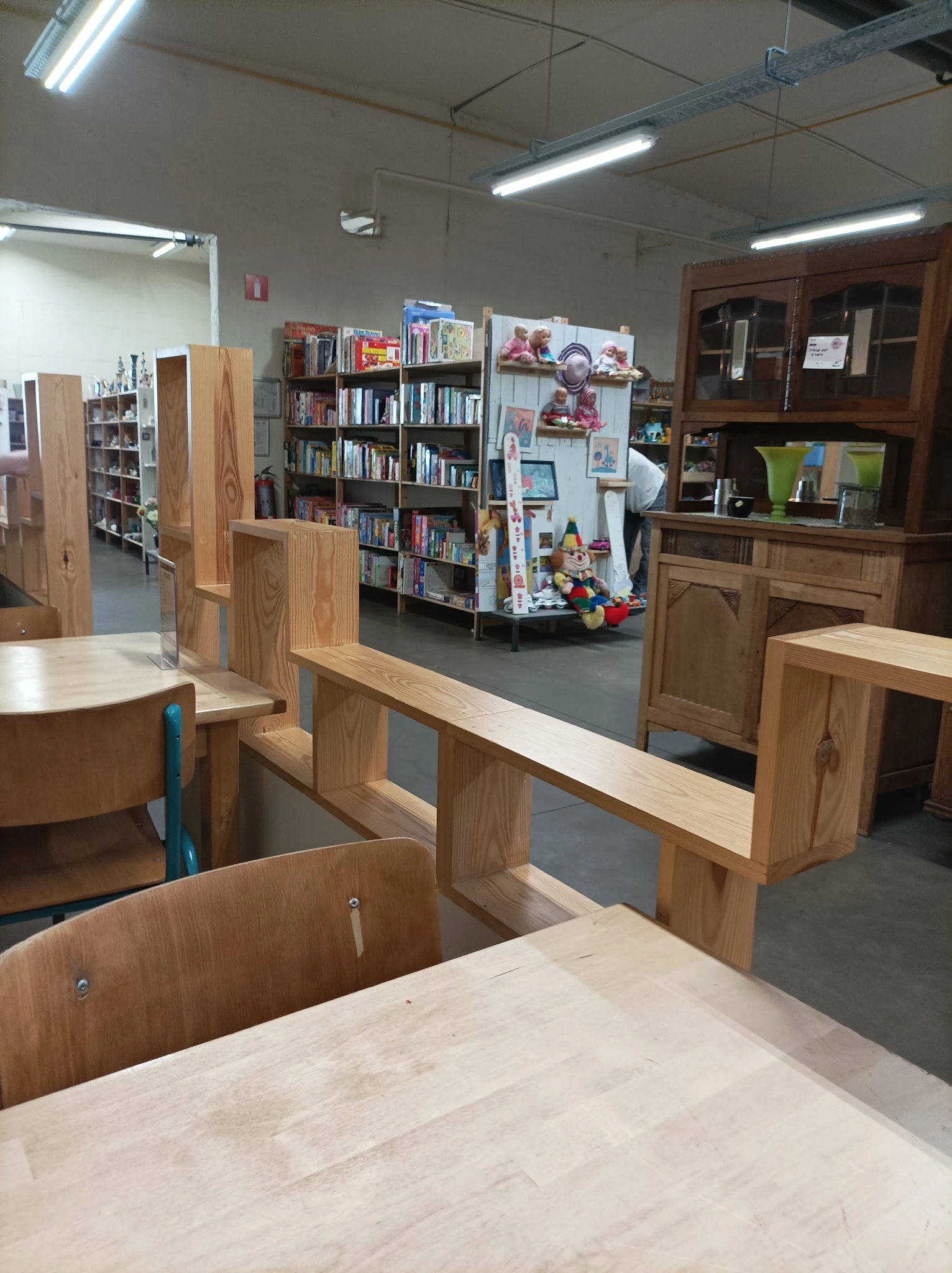 Winkelvloer met houten meubels, boekenrekken en kastjes vol tweedehands spullen