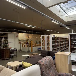 Ruime winkelruimte met stellingen, meubels, huishoudartikelen en diverse tweedehandsartikelen onder halogeenverlichting