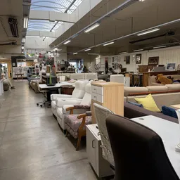 Ruim winkelinterieur met diverse meubels, stoelen en bankstellen uitgestald langs de winkelvloer