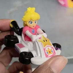Close-up van een speelgoedfiguur: Prinses Peach uit Mario Kart in een roze racewagen