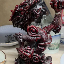 Close-up van een rood-zwart decoratief drakenolifantbeeldje uit keramiek of porselein
