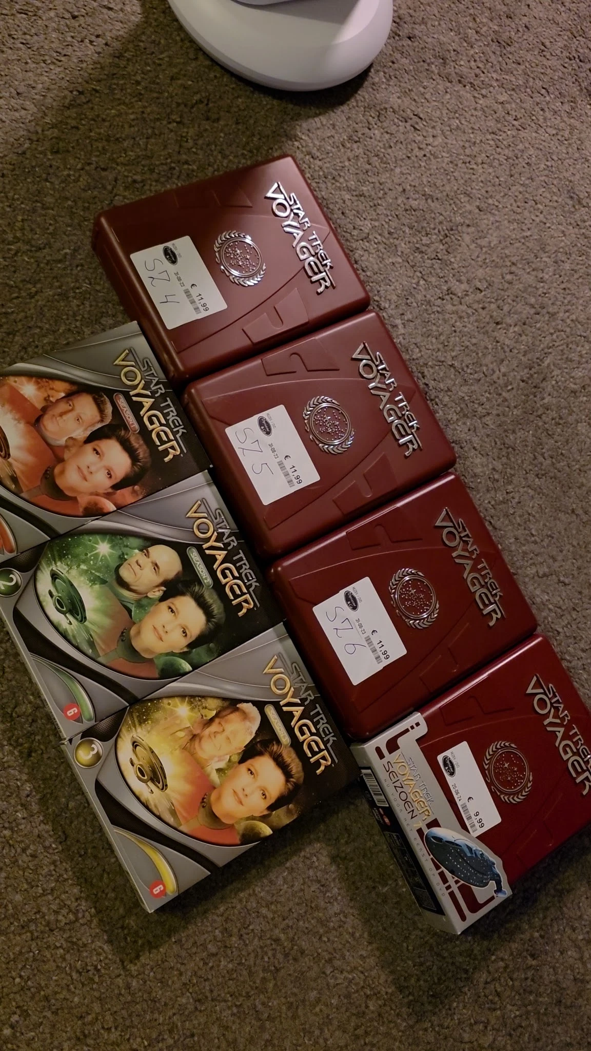 Stapel dvd-boxen van de serie Dawson's Creek in rood, links enkele dvd-hoezen op de grond