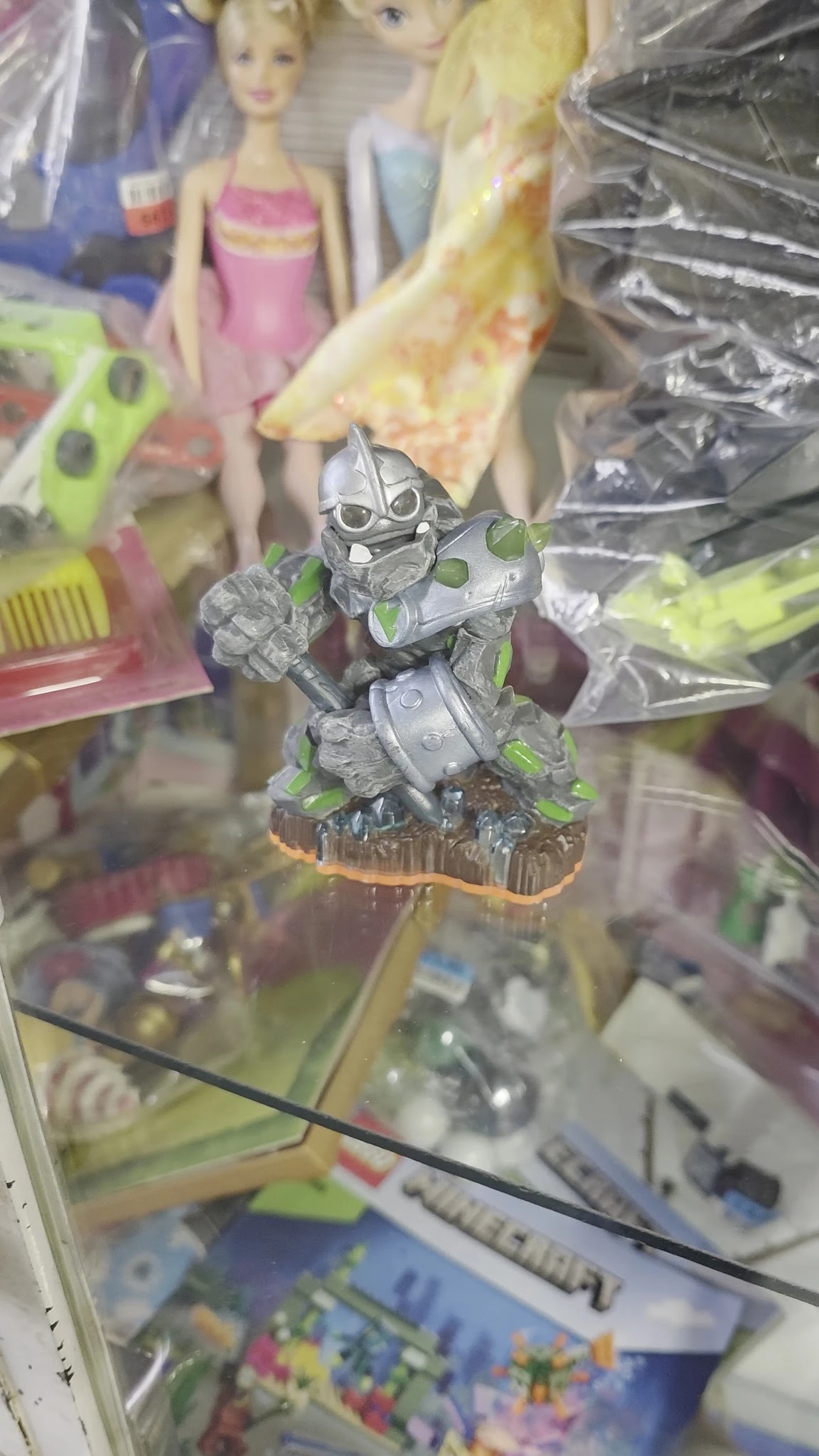 Close-up van een grijs speelgoedactiefiguur met groen accenten op houten voet