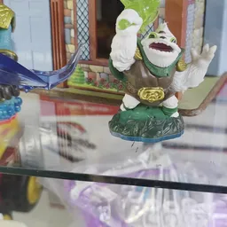 Close-up van een groene speelfiguur met witte details en gouden accessoires