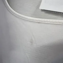 Close-up van een wit katoenen t-shirt met zichtbare textuur en naad