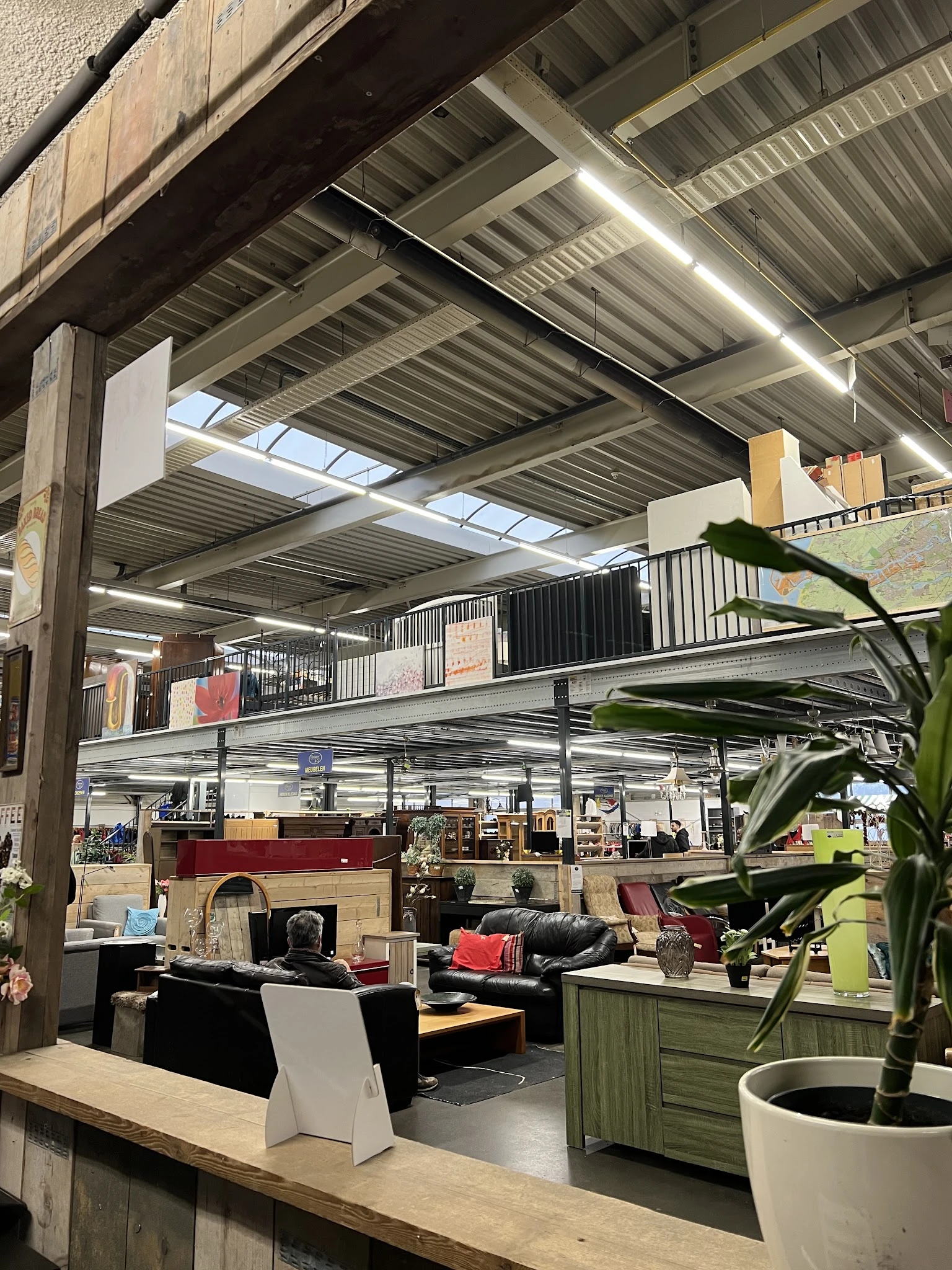 Industrieel interieur van kringloopwinkel met mezzanine, stellingen, meubels en diverse spullen