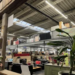 Industrieel interieur van kringloopwinkel met mezzanine, stellingen, meubels en diverse spullen