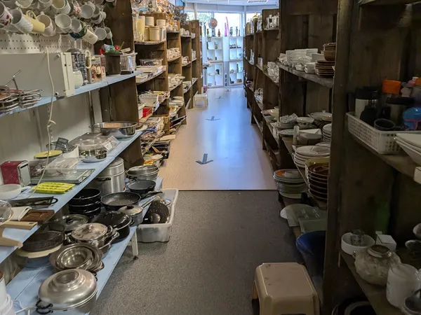 Winkelgang met stellingen vol servies, pannen en keukengerei aan beide zijden