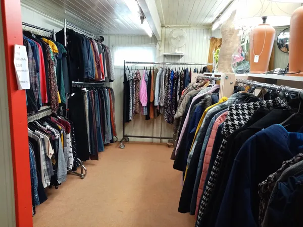 Binnenzicht van kringloopwinkel met rekken vol tweedehands kleding langs de wanden