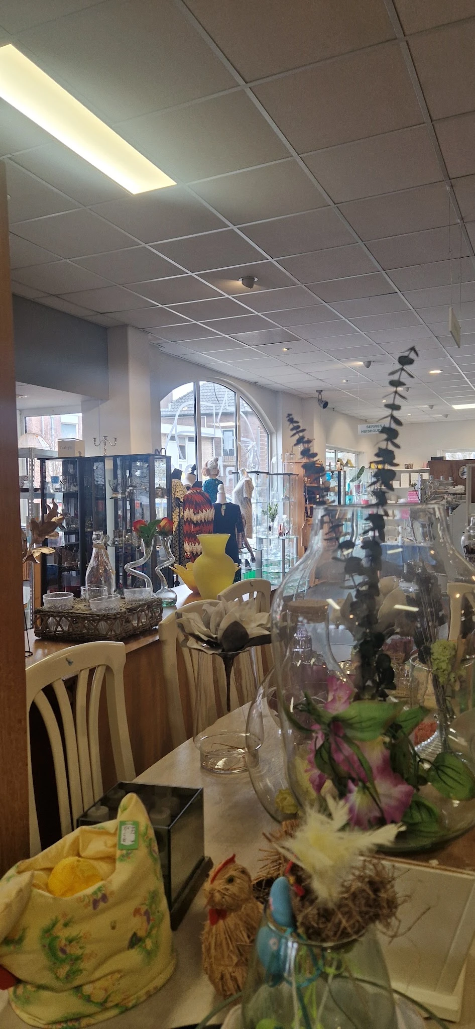 Winkelinterieur met displaykasten, kunstobjecten en decoraties, grote raam op straat