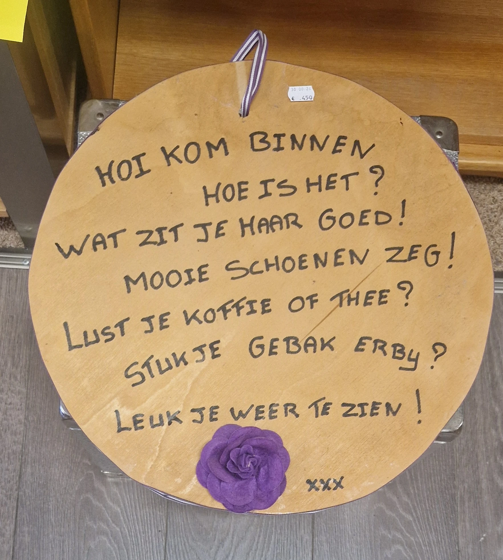 Houten bord met handgeschreven Nederlandse teksten over welkom en gezelligheid in de winkel