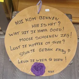 Houten bord met handgeschreven Nederlandse teksten over welkom en gezelligheid in de winkel