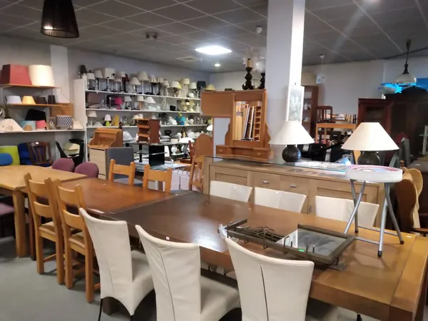 Winkelvloer met houten tafels, stoelen en diverse huisraad in een kringloopwinkel