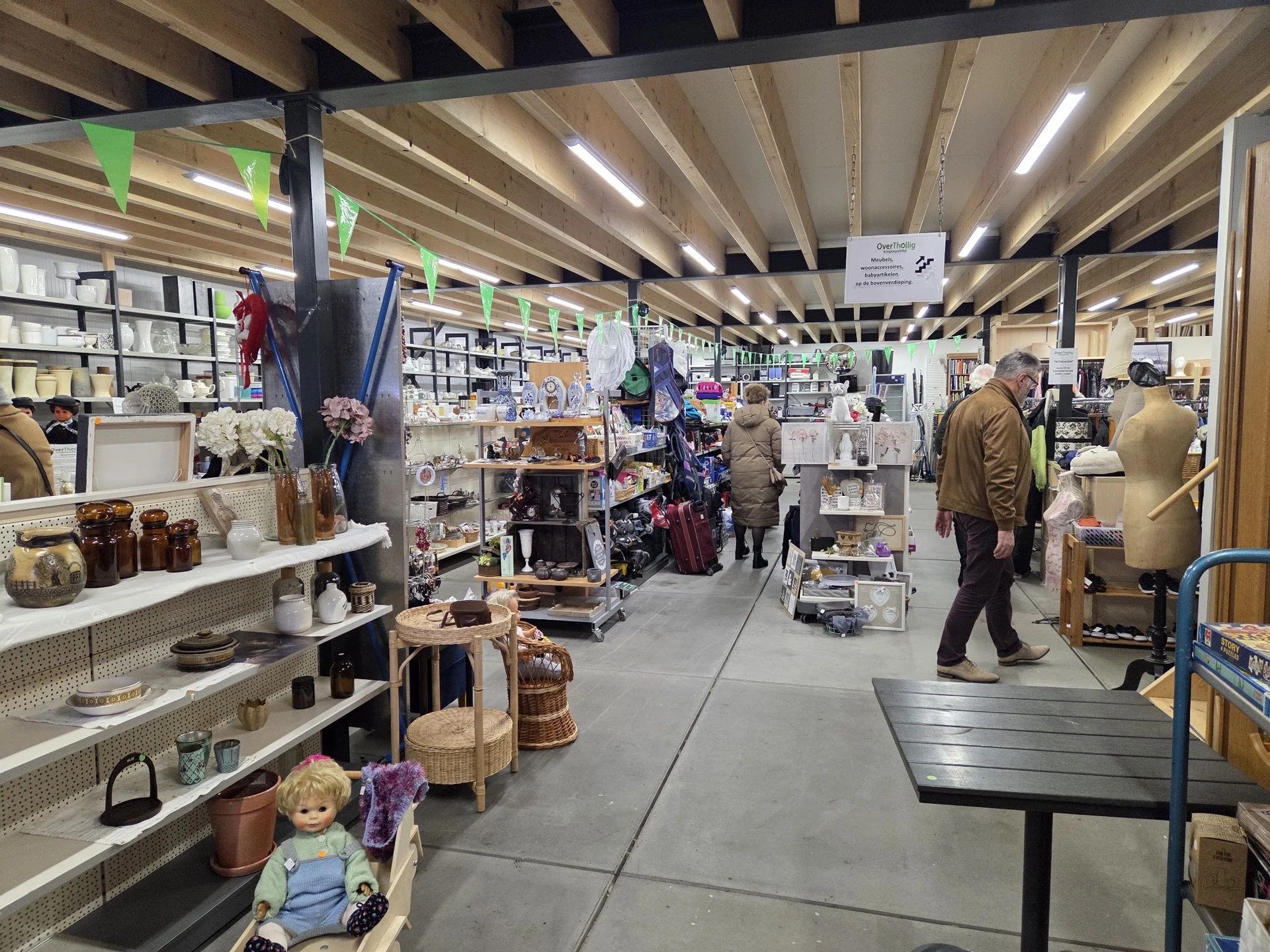 Winkelvloer van kringloopwinkel met stellingen vol huishoudartikelen, decoratie en gebruiksvoorwerpen