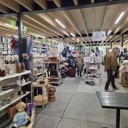 Winkelvloer van kringloopwinkel met stellingen vol huishoudartikelen, decoratie en gebruiksvoorwerpen