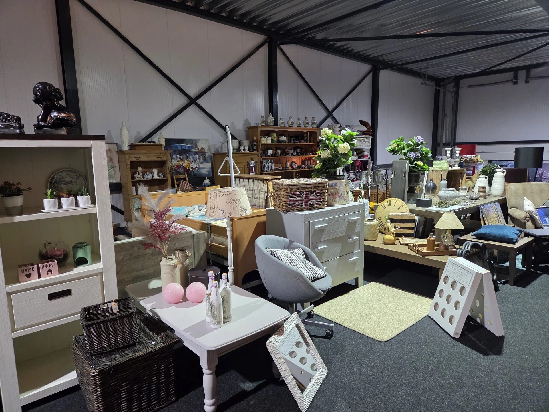 Winkelvloer met diverse meubels, stellingen en decoratieve artikelen in een kringloopwinkel