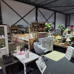 Winkelvloer met diverse meubels, stellingen en decoratieve artikelen in een kringloopwinkel