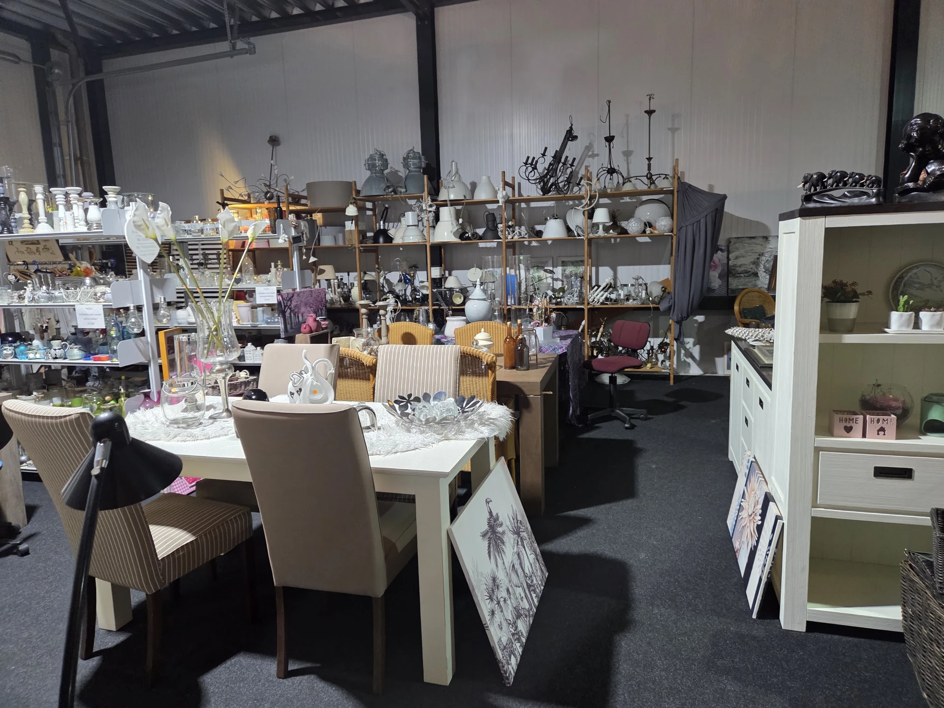 Overzicht van winkelvloer met tafels, stoelen, kasten en diverse huishoudelijke spullen en decoratieartikelen.