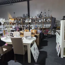 Overzicht van winkelvloer met tafels, stoelen, kasten en diverse huishoudelijke spullen en decoratieartikelen.