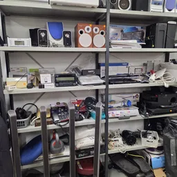 Metalen stellingen met elektronische apparaten, speakers, computers en huishoudelijke spullen